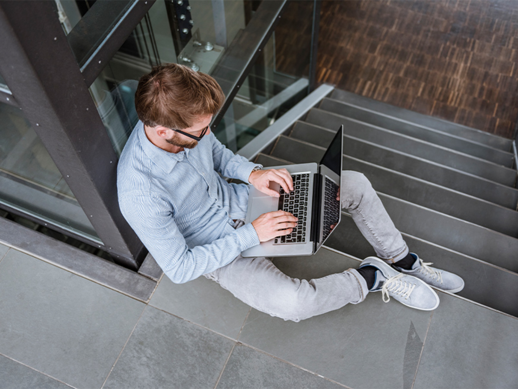 Wiki Schmuckbild 14 Ein Mann sitzt auf einer Treppe und arbeitet an einem Laptop